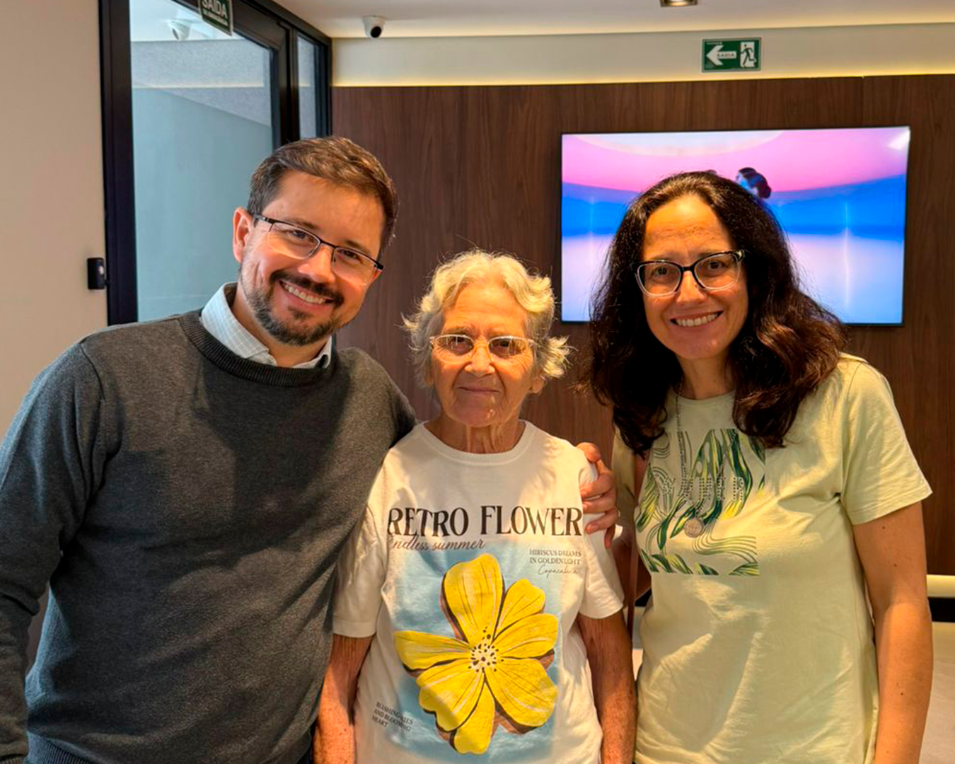 Paciente sorridente ao lado do Dr. Paulo Fernando na recepção da Oraliv
